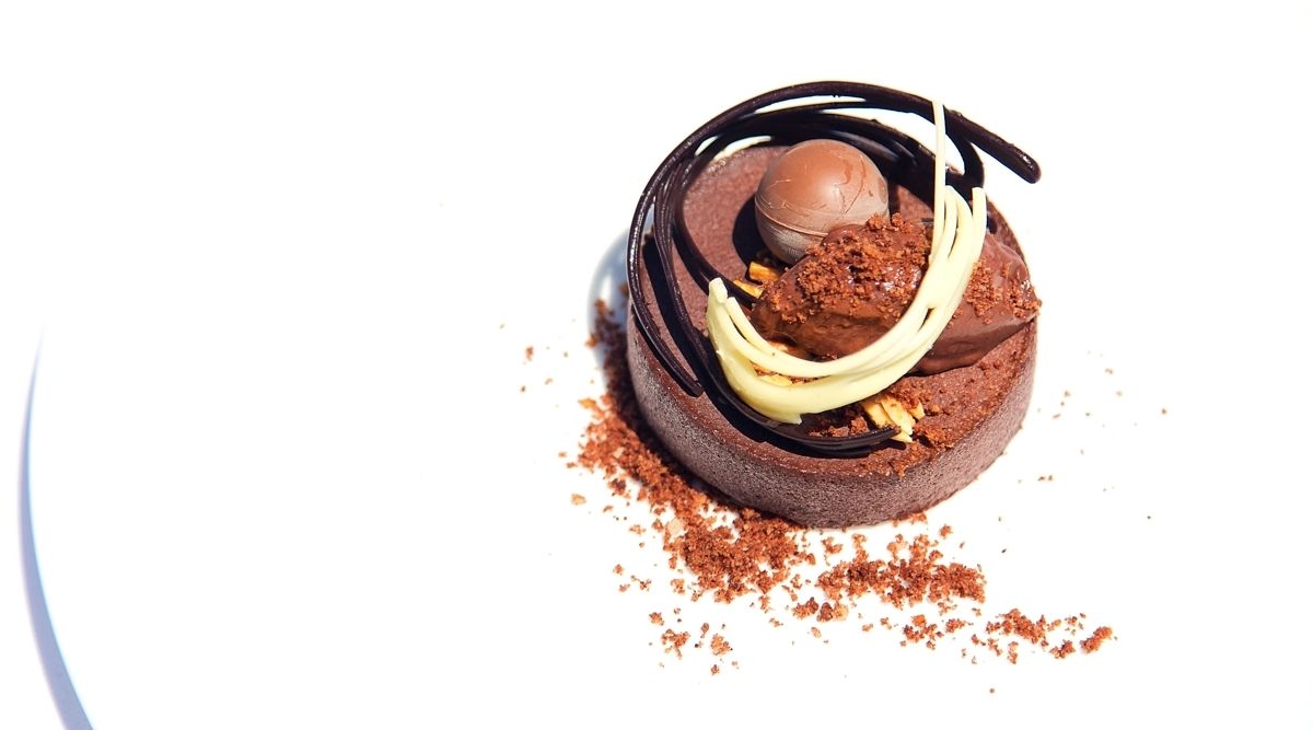 A dessert with chocolate elements and a chocolate shell on a white background.