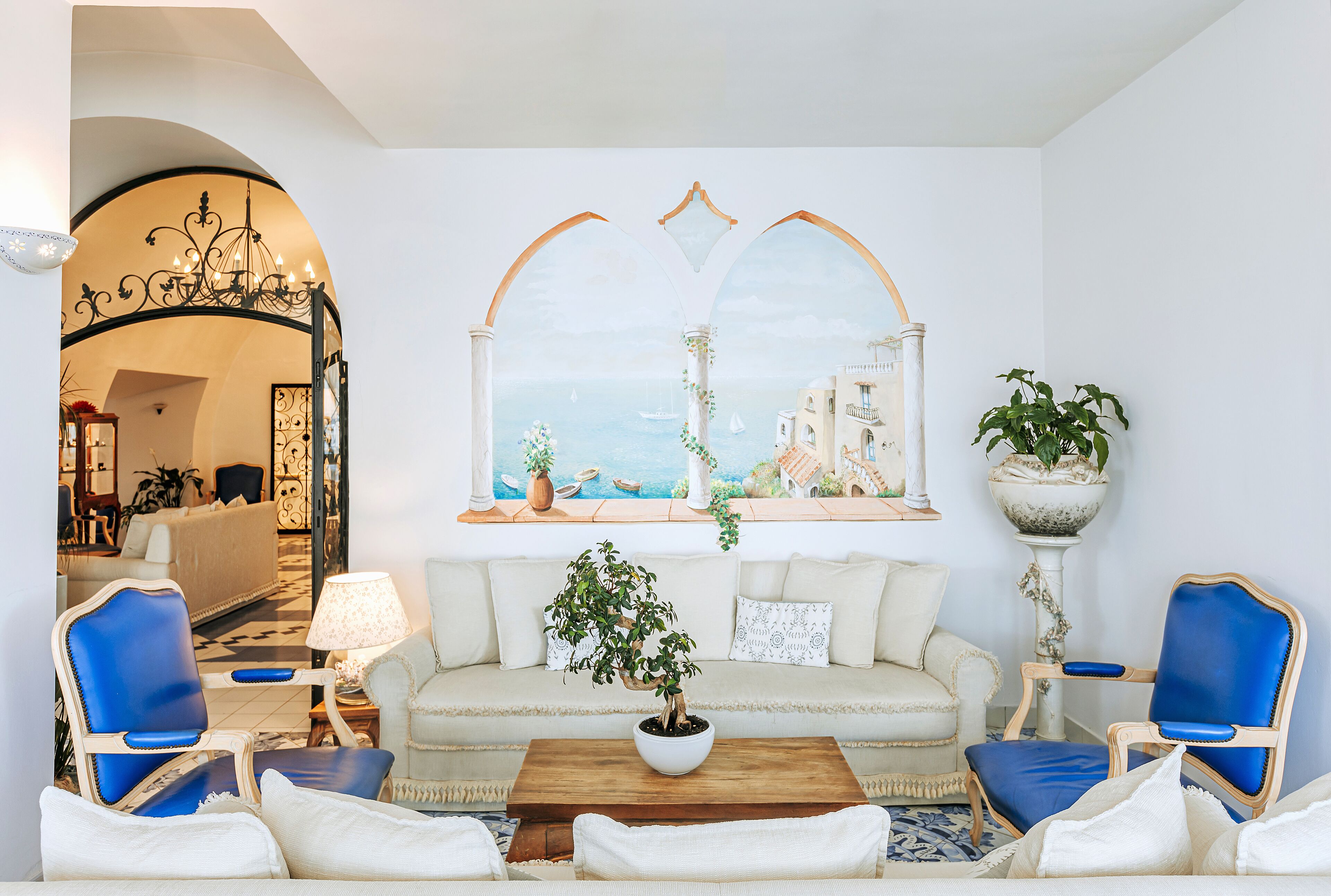 A living room with a sofa, two blue armchairs, a coffee table, and a potted plant.