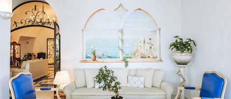A living room with a sofa, two blue armchairs, a coffee table, and a potted plant.