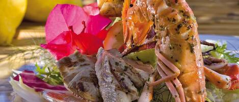 A seafood dish with grilled fish and shrimp, garnished with herbs and flowers.