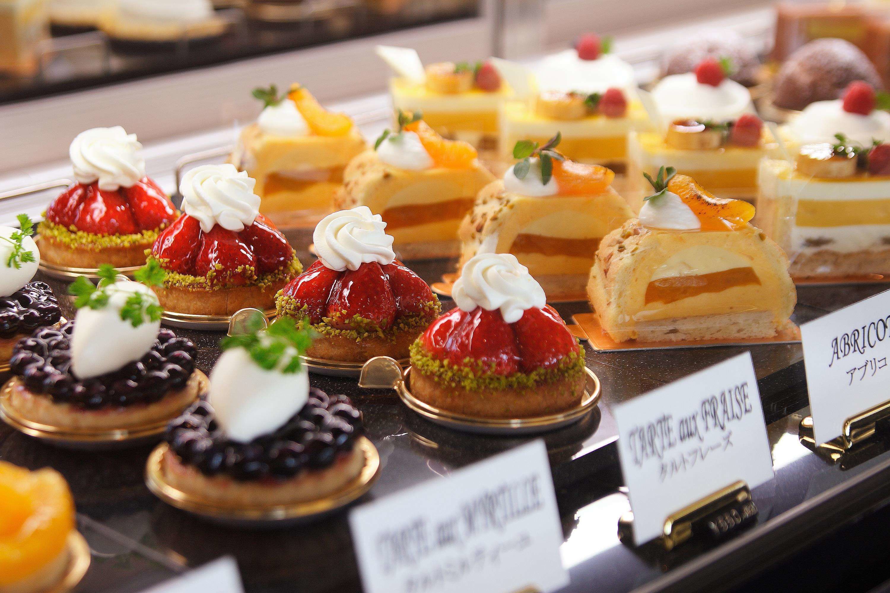 A variety of desserts on display, including cakes with whipped cream and fruit toppings.