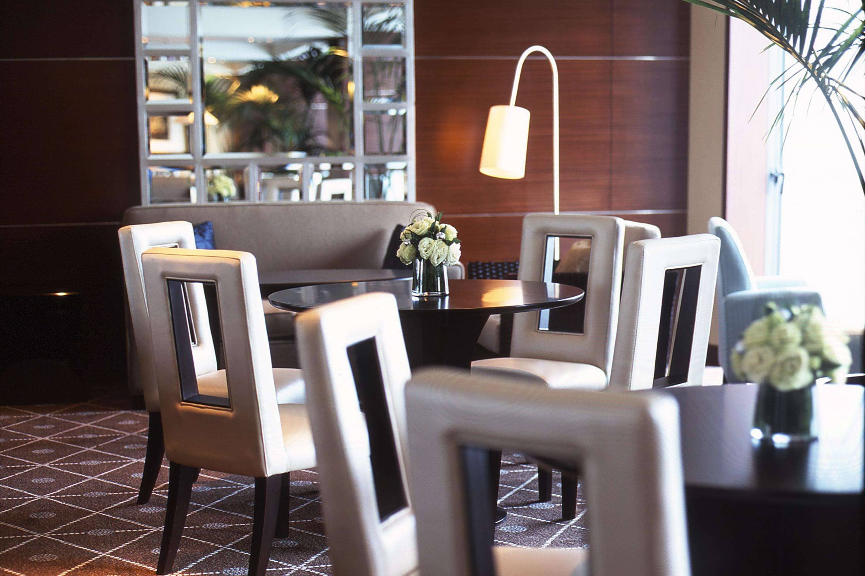 A dining area with a round table, four chairs, and a vase of flowers.
