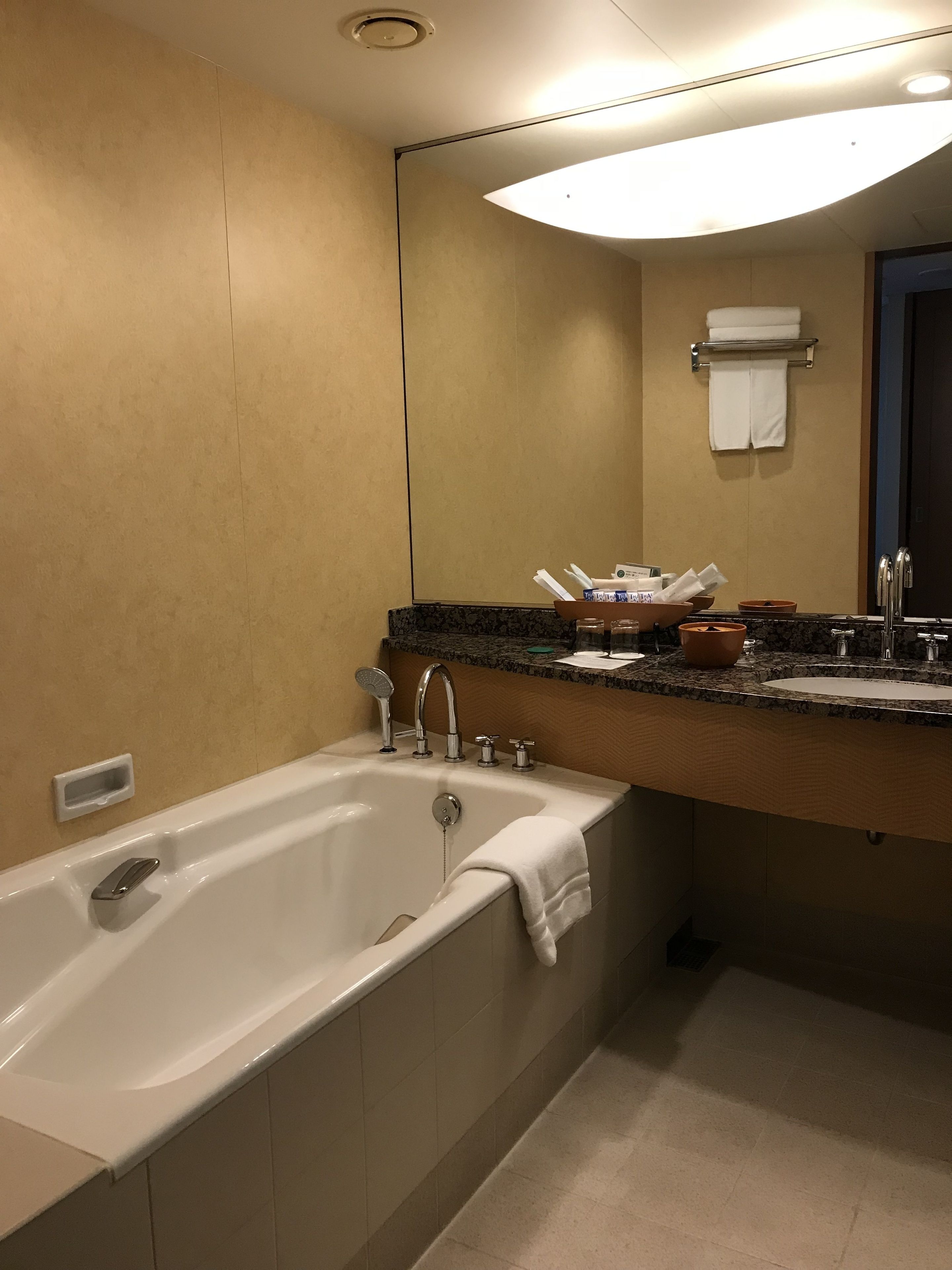 A modern bathroom with a large bathtub, a sink with a mirror, and a towel rack.