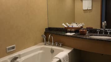 A modern bathroom with a large bathtub, a sink with a mirror, and a towel rack.