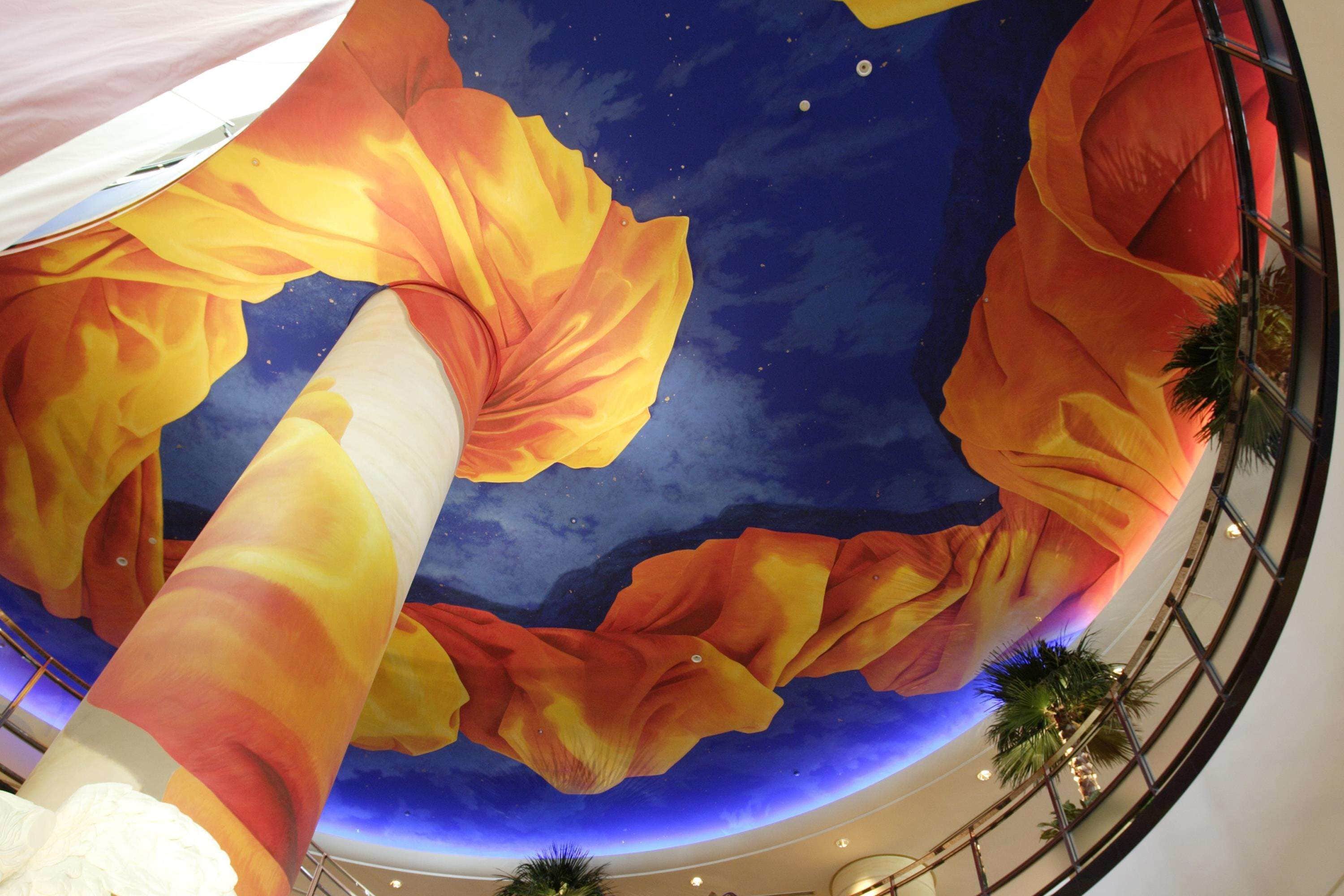 A ceiling with a large, colorful mural of flowing fabric.