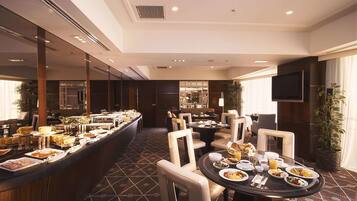 Un comedor de hotel con servicio de buffet, mesas y una televisión.