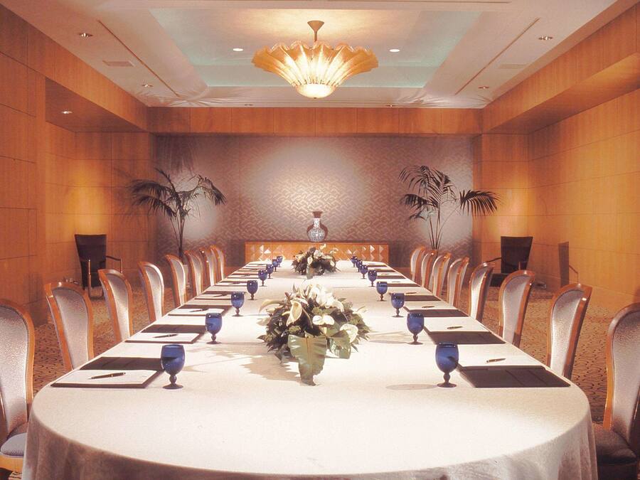 Ein Konferenzraum mit einem langen Tisch, Stühlen und einer Kronleuchter.