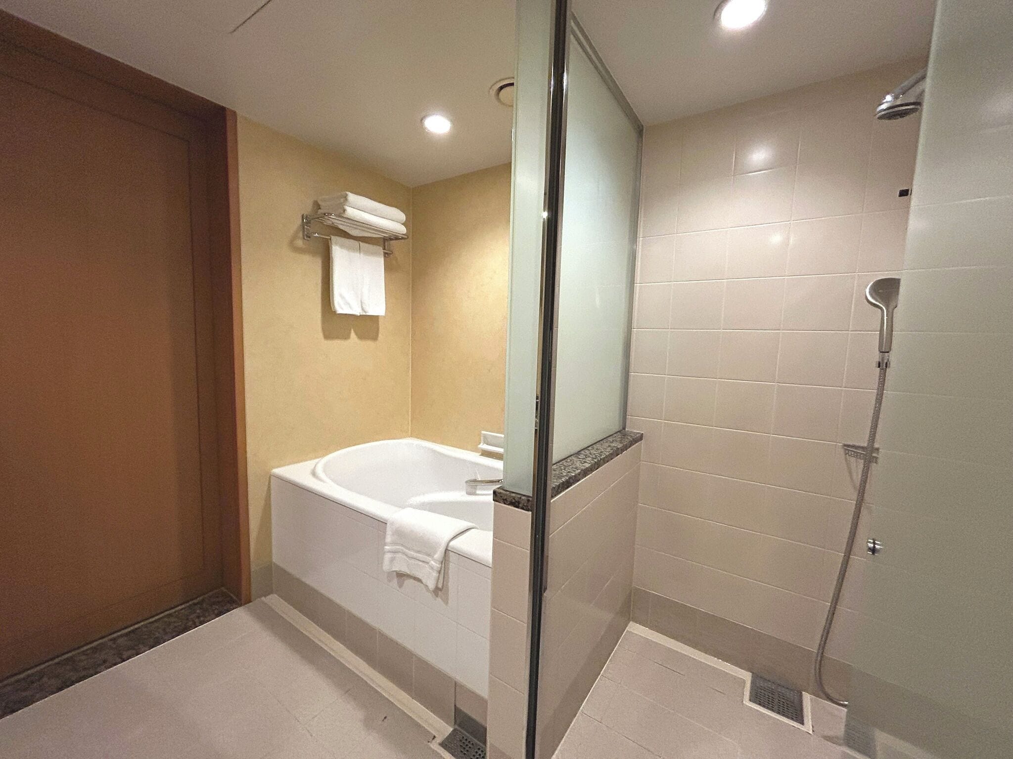 A modern bathroom with a bathtub, a glass-enclosed shower, and a towel rack.