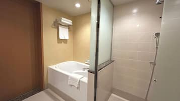 A modern bathroom with a bathtub, a glass-enclosed shower, and a towel rack.