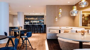 Uma área de bar moderna, com balcão, assentos e luminárias pendentes.