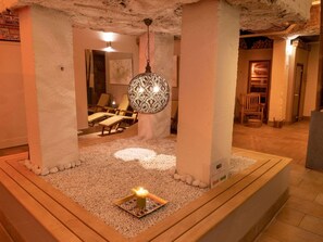 A spa area with a patterned light fixture, a candle on a tray, and lounge chairs. - Novotel Den Haag World Forum (The Hague)