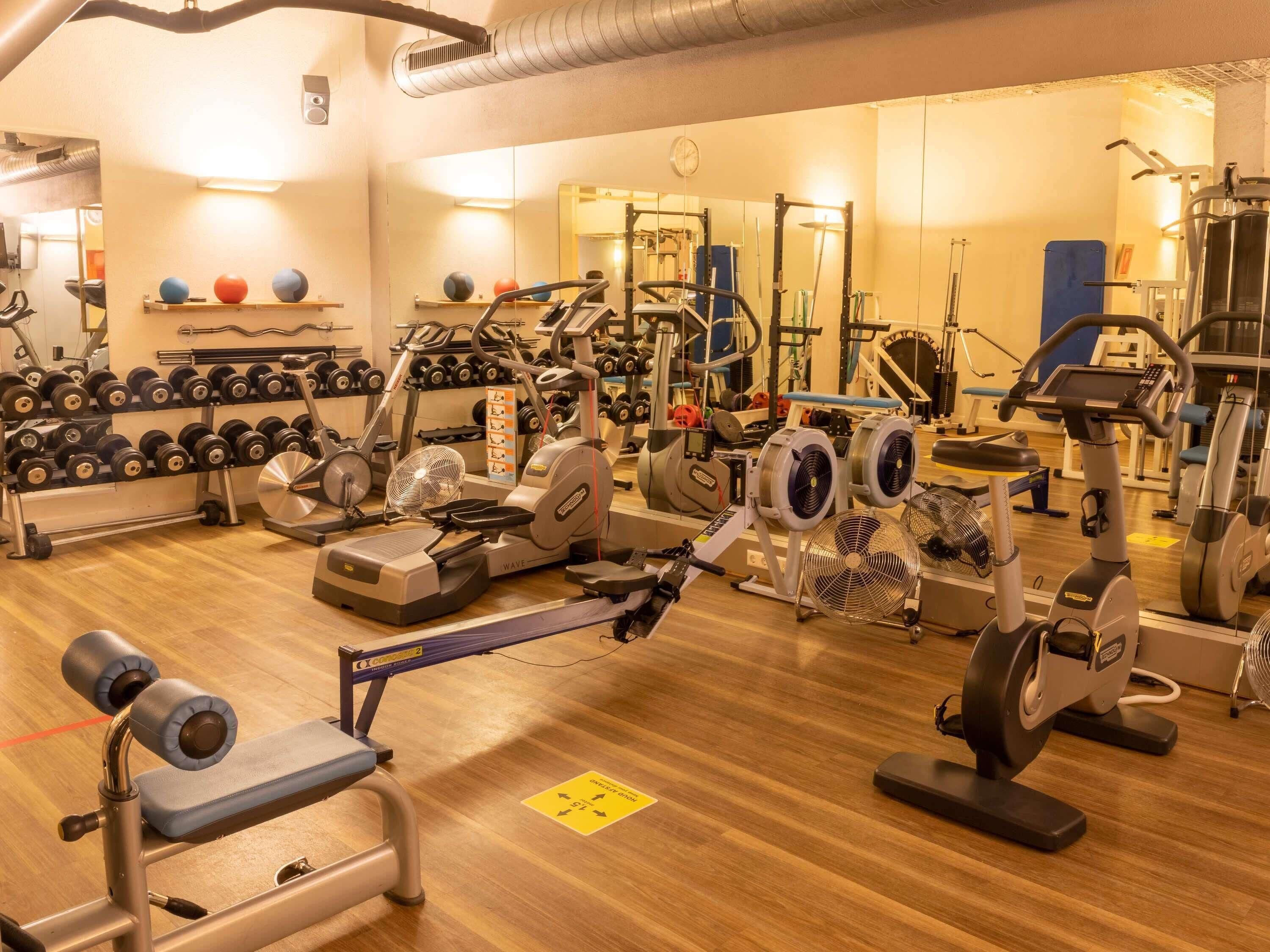 A gym with various exercise equipment, including treadmills, stationary bikes, and weight machines.