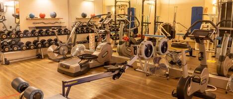 Un gimnasio con diversos equipos de ejercicio, como cintas de correr, bicicletas estáticas y máquinas de pesas.