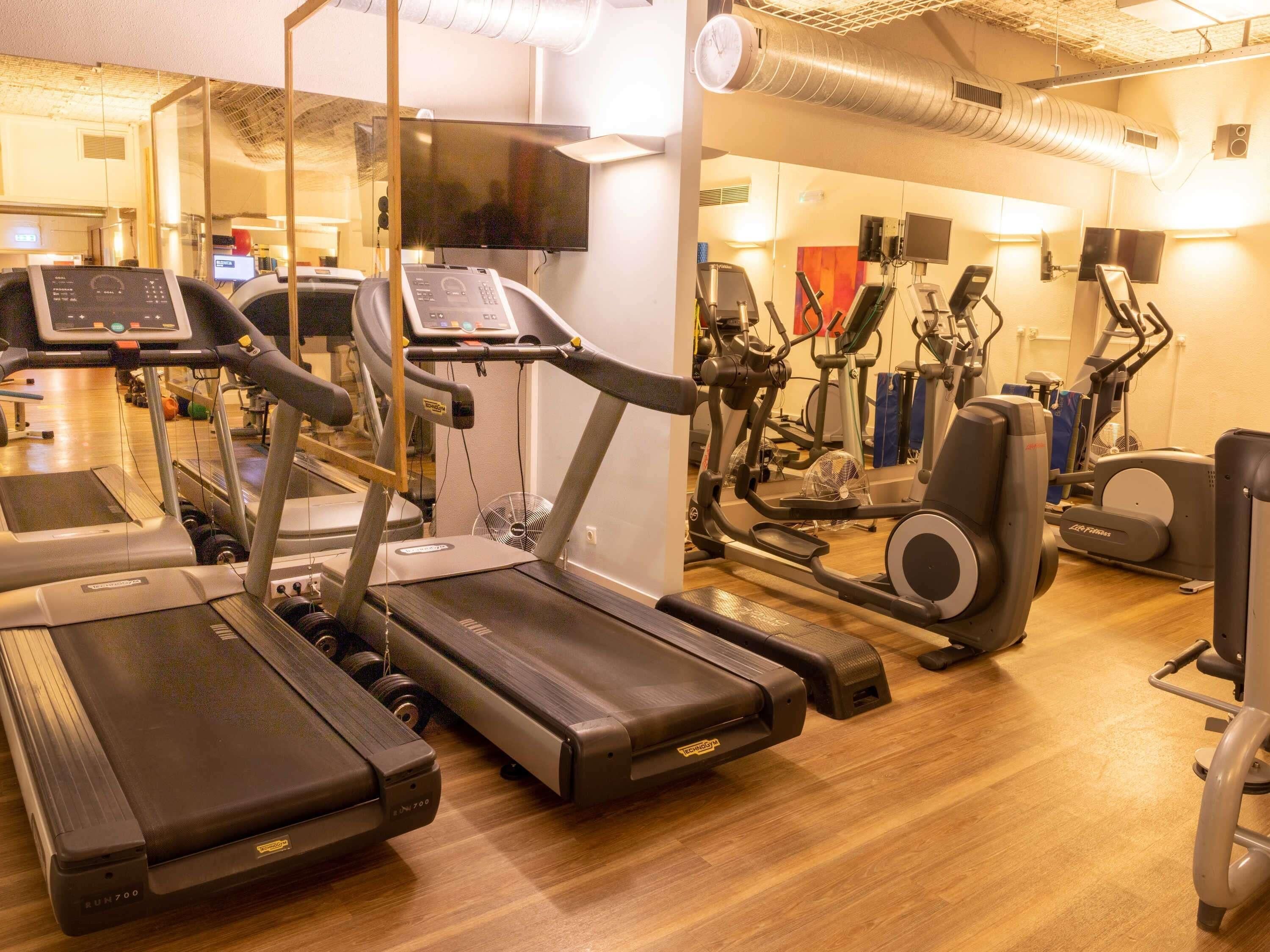 A gym with treadmills, stationary bikes, and elliptical machines.