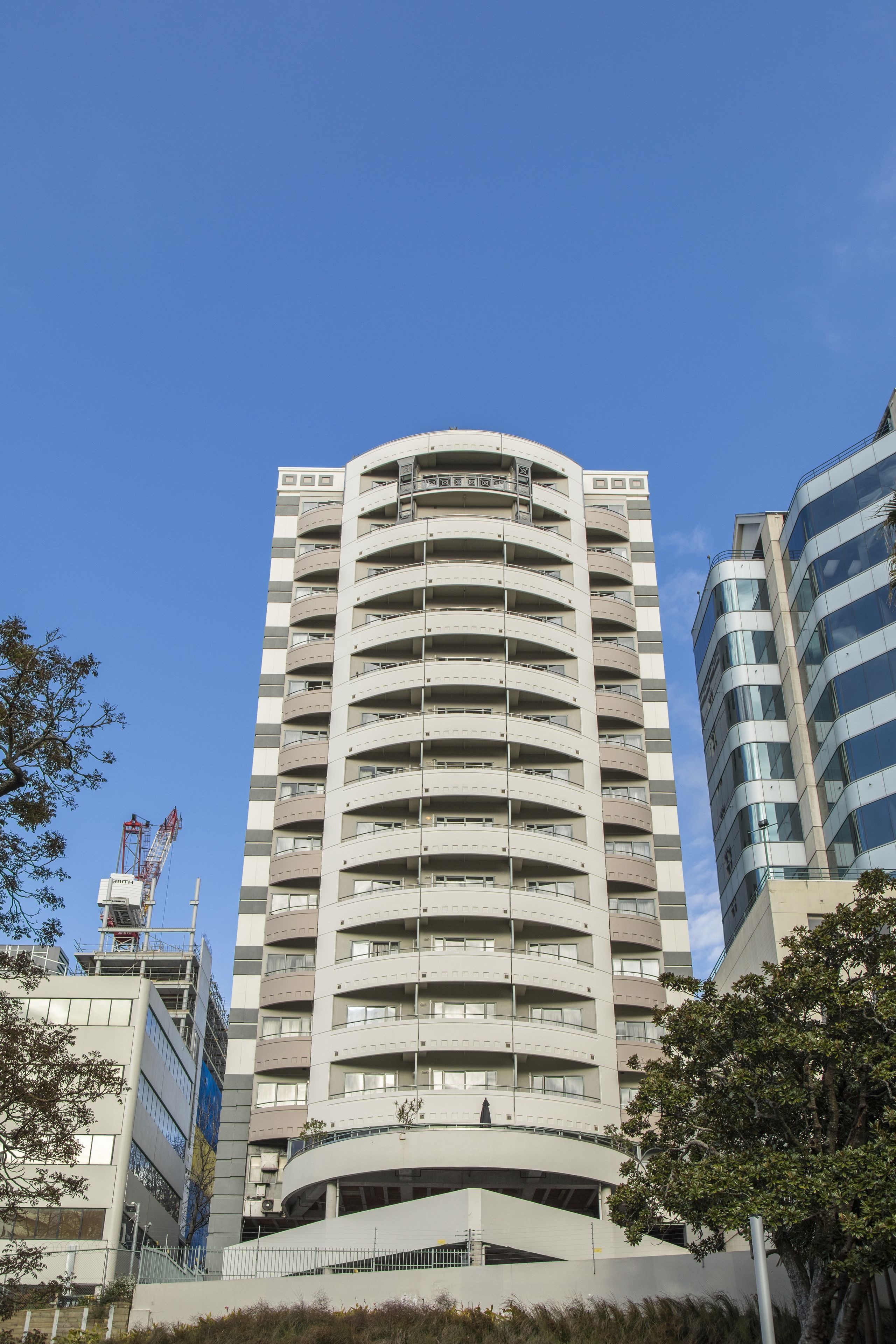 A multi-story building with a curved facade, balconies, and a flat roof.