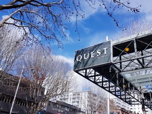 A sign for 'QUEST Auckland' with a modern metal structure and a clear blue sky in the background. - Quest Auckland (Auckland)