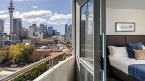 Habitación de hotel con un ventanal que ofrece vista al horizonte de la ciudad, incluyendo una torre destacada.