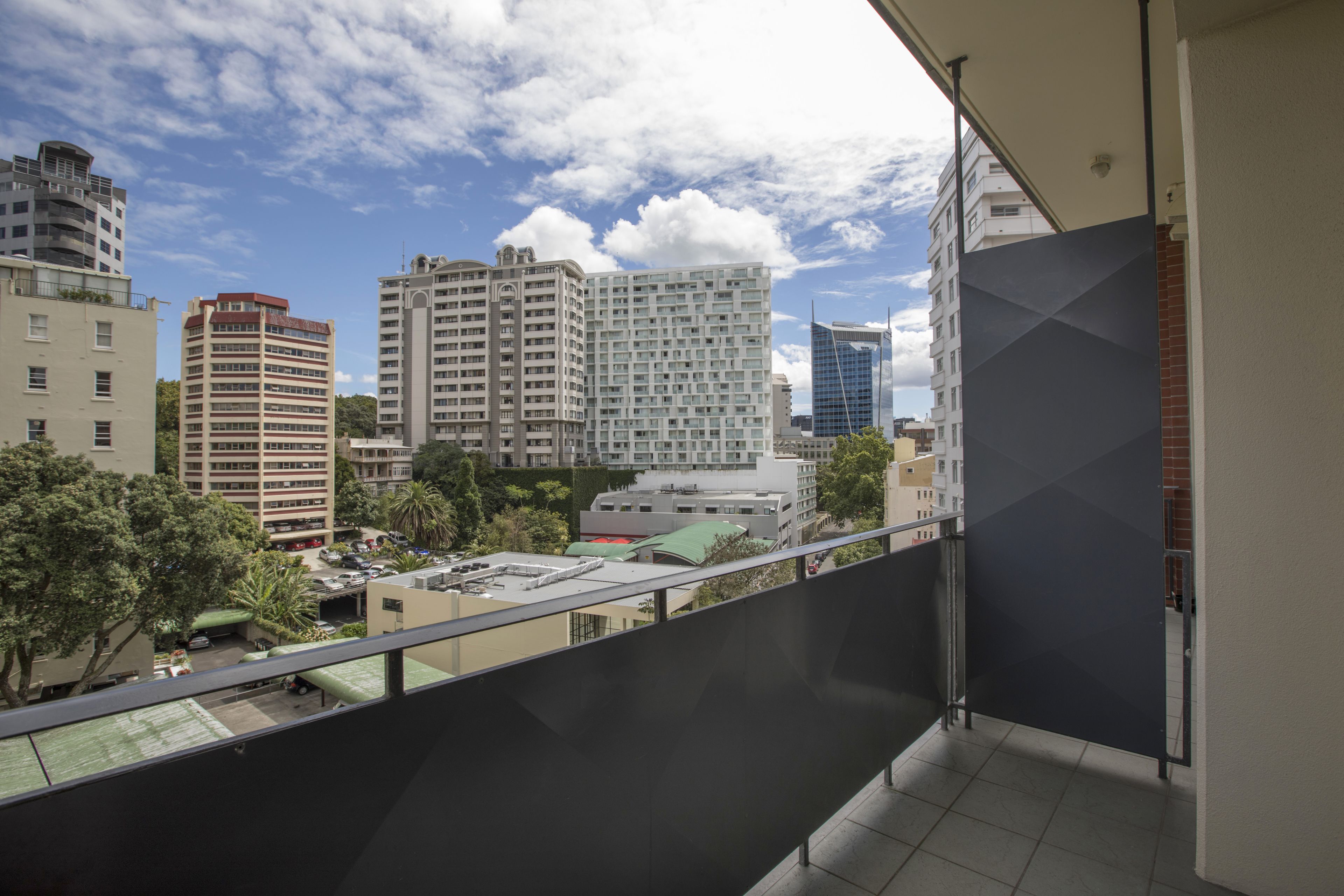 A balcony with a view of a cityscape, including various buildings and a clear sky.