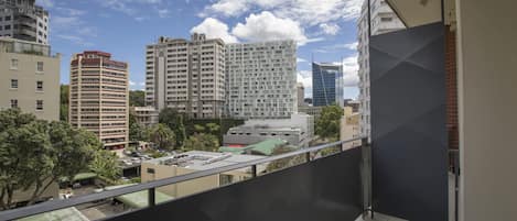A balcony with a view of a cityscape, including various buildings and a clear sky.