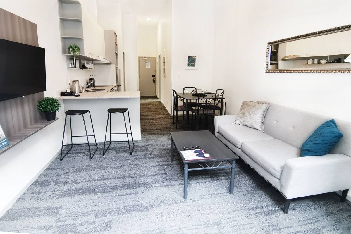 A compact living space with a kitchenette, a sofa, a coffee table, and a dining area.