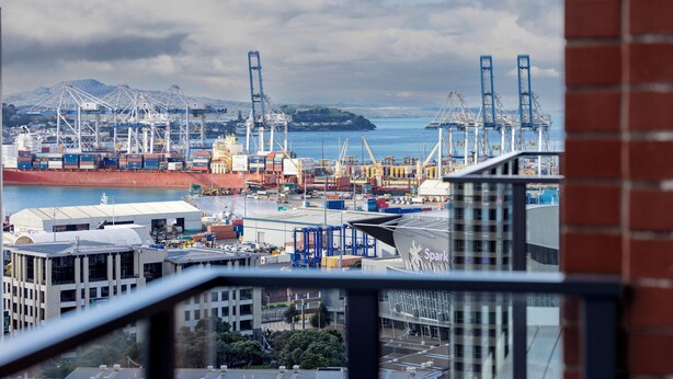 Un puerto con contenedores de carga, grúas y un gran barco.