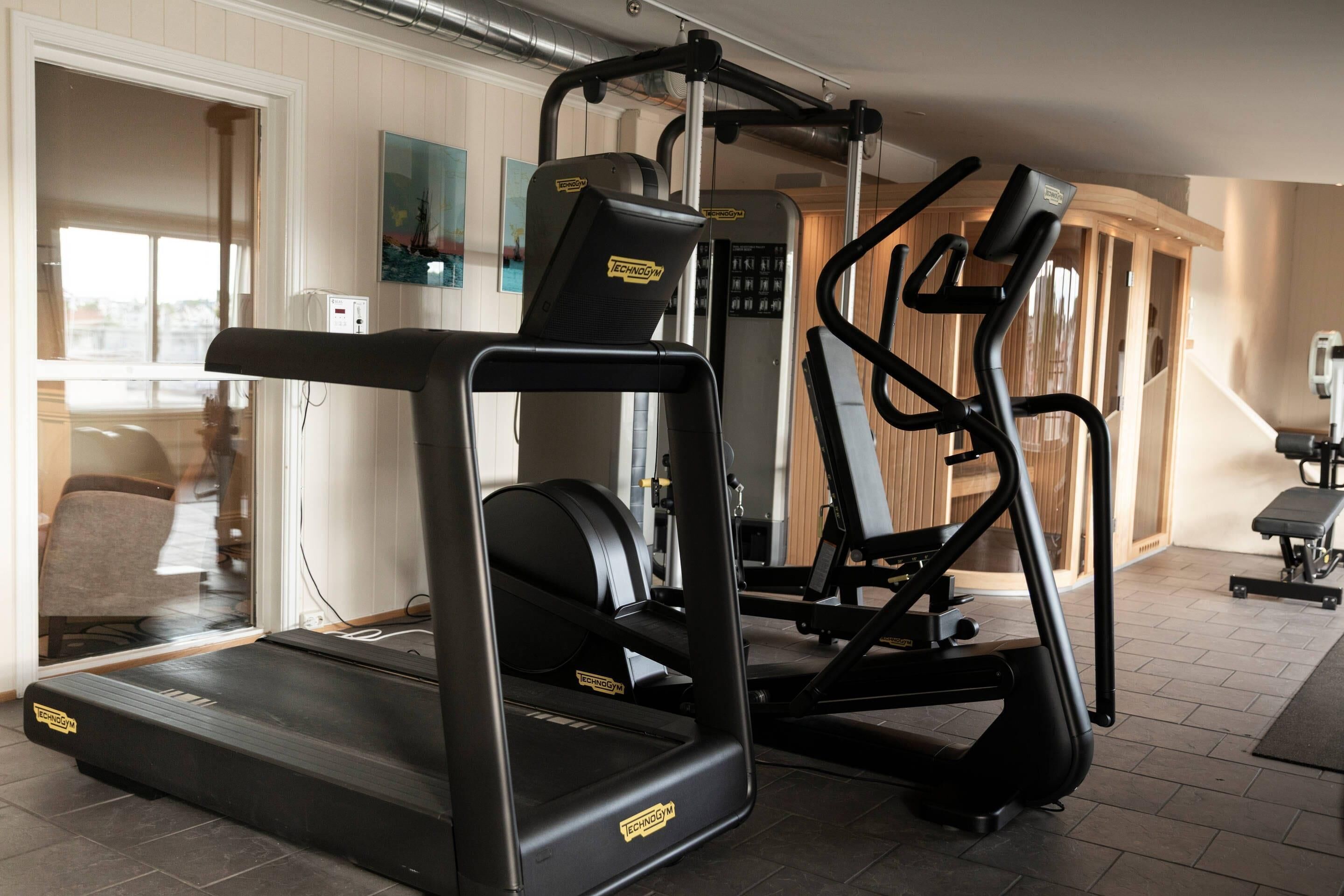 A home gym with a treadmill, elliptical, and weight machine.