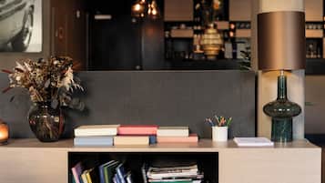 A modern reception desk with a vase of dried flowers, a stack of books, and a lamp.