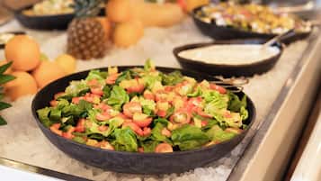 A buffet with a variety of dishes including a salad, fruits, and a creamy soup.