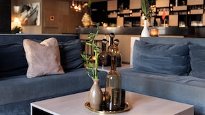 Una sala de estar moderna con un sofá, una mesa de centro y elementos decorativos, incluyendo un jarrón con una planta y una botella.