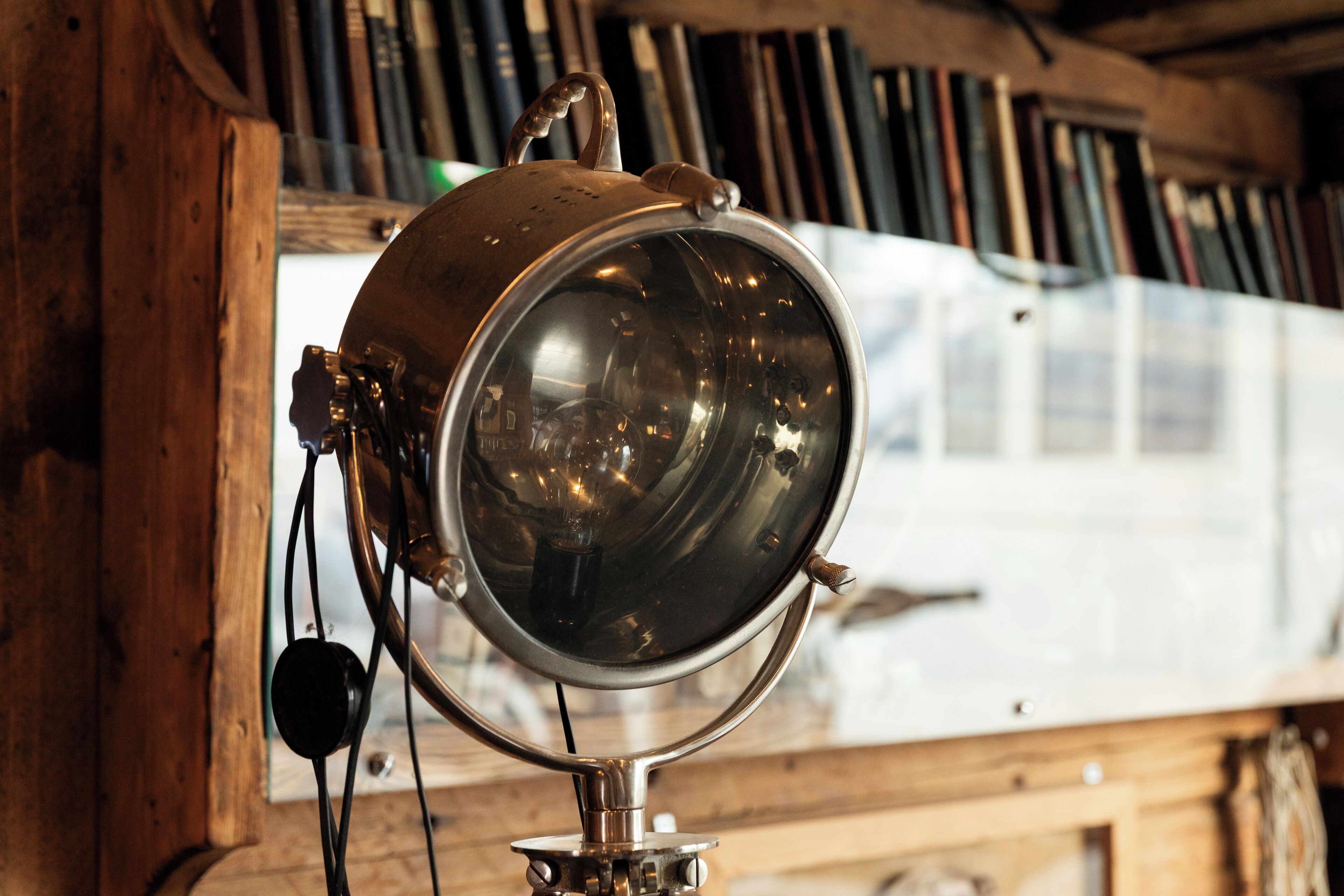 Eine Vintage-Lampe mit reflektierender Oberfläche, an einer Holzvertäfelung befestigt.