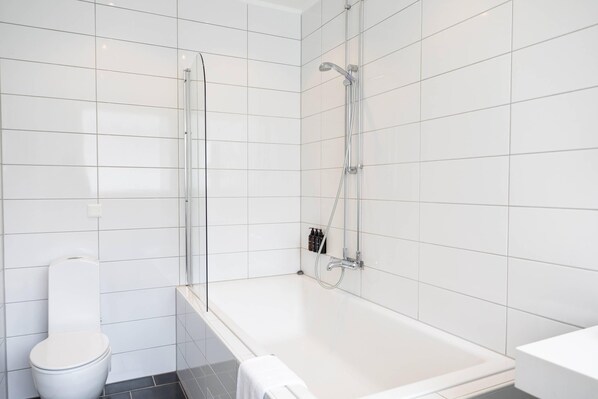 A modern bathroom with a glass-enclosed shower, a white toilet, and a bathtub.
