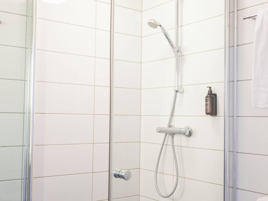 A modern shower with a handheld showerhead and a fixed wall-mounted showerhead.
