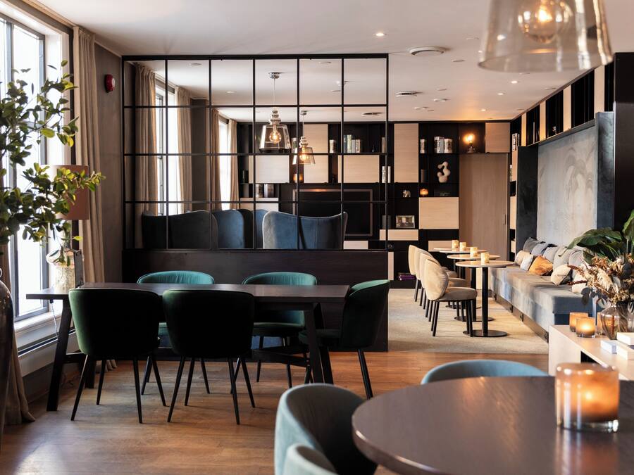 A modern lounge area with a seating arrangement, a dining table, and a bookshelf.
