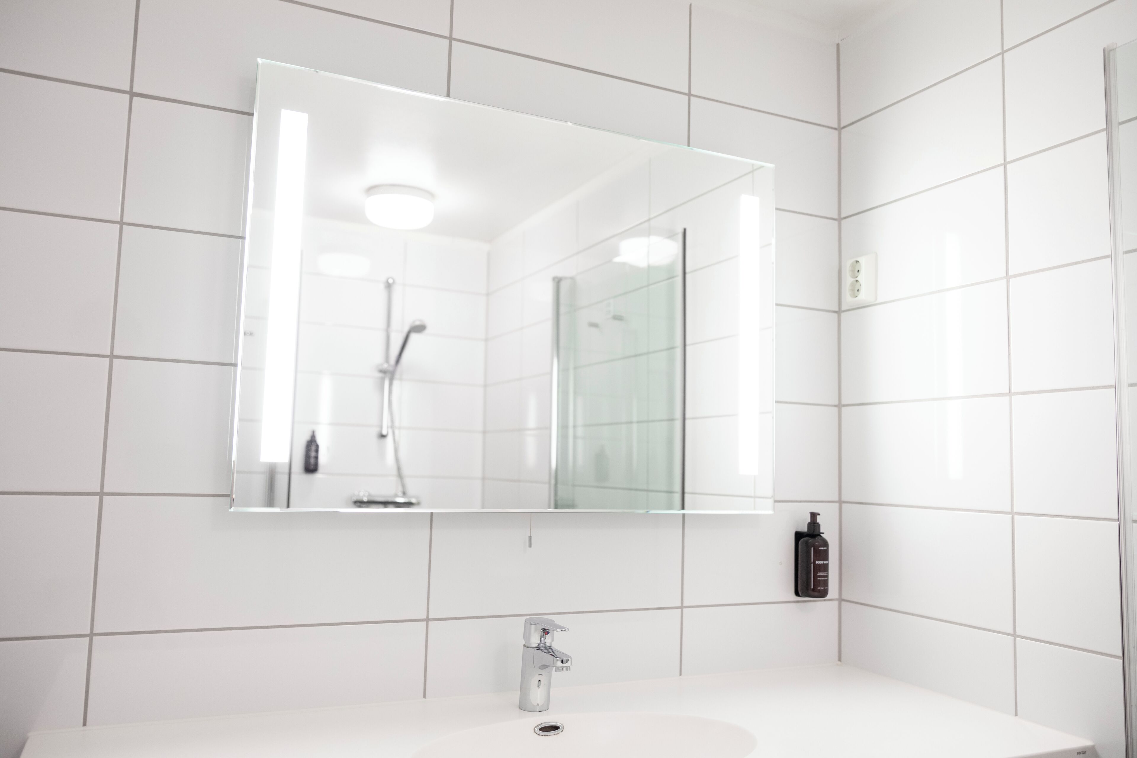 A modern bathroom with a white sink, a large mirror, and a glass shower enclosure.