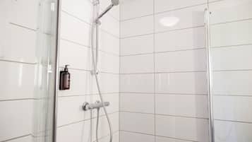 Un baño moderno con paredes de azulejos blancos, cabina de ducha de vidrio y ducha de mano.