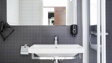 A bathroom with a white sink, a mirror, a hairdryer, and a shower.