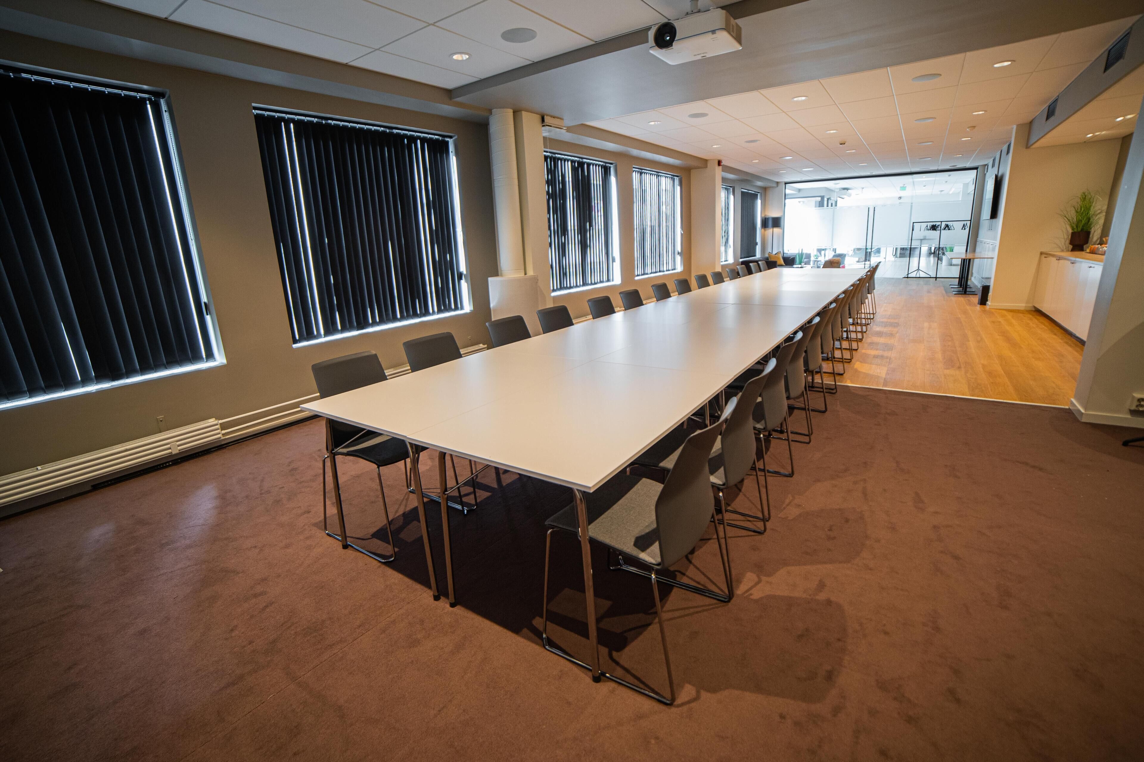 A conference room with a long table, chairs, and large windows.