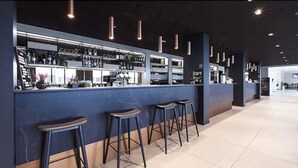 A bar area with high shelves stocked with bottles, a counter, and three stools. - Scandic Victoria Floro (Floro)