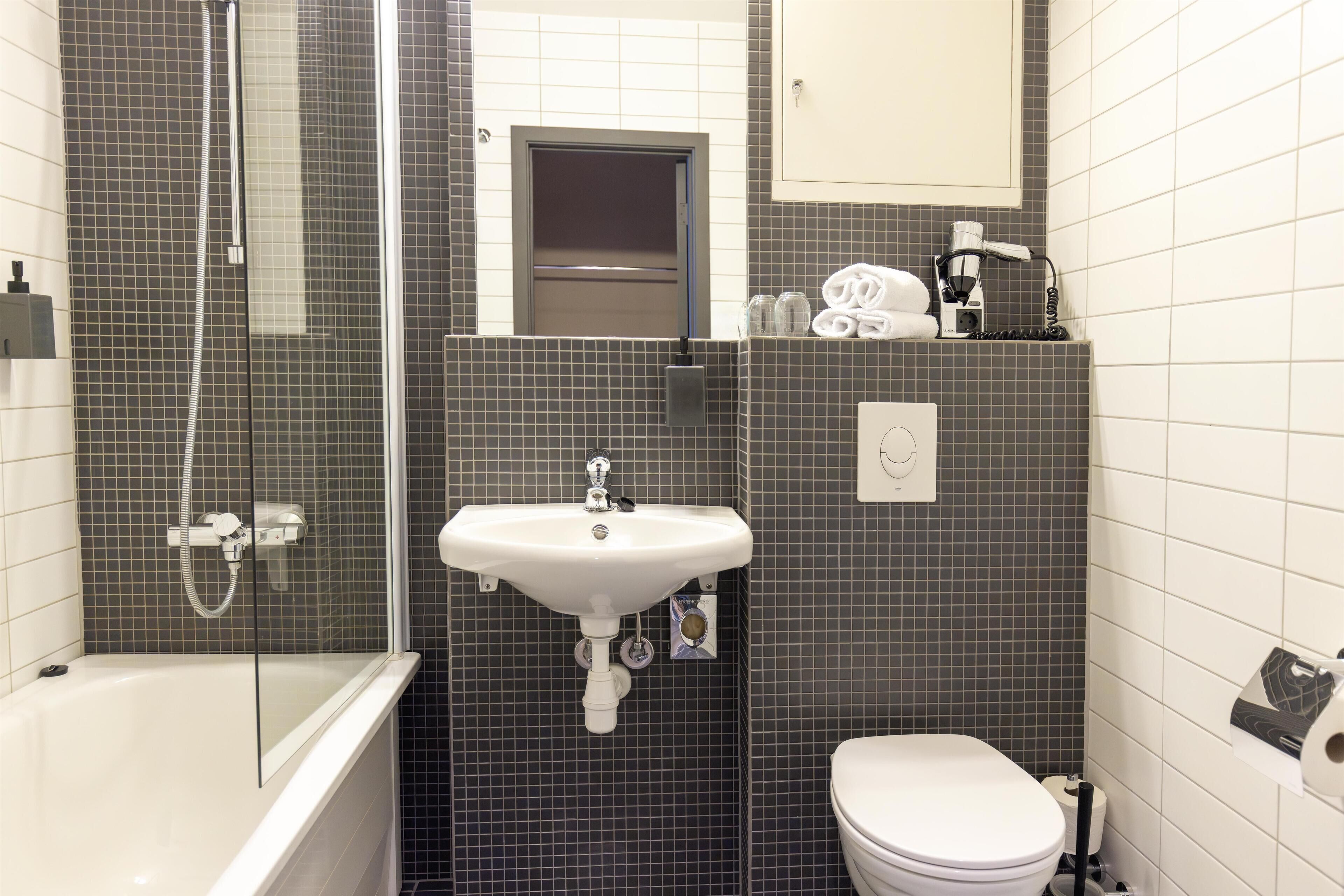 Un baño con bañera, lavamanos, inodoro y ducha.