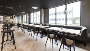 A modern dining area with high tables, bar stools, and a long bench. - Scandic Victoria Floro (Floro)