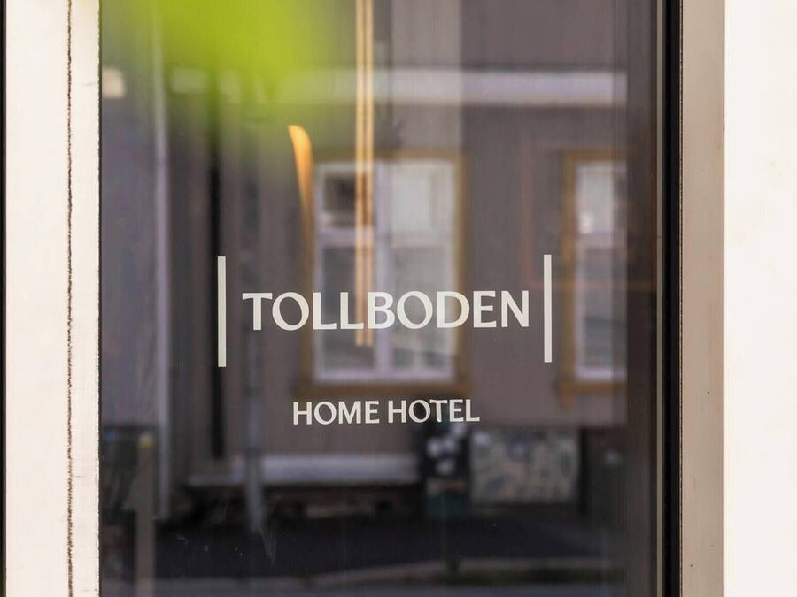 Ein Fenster mit dem Schriftzug 'TOLLBODEN HOME HOTEL' und einem unscharfen Hintergrund eines Gebäudes.