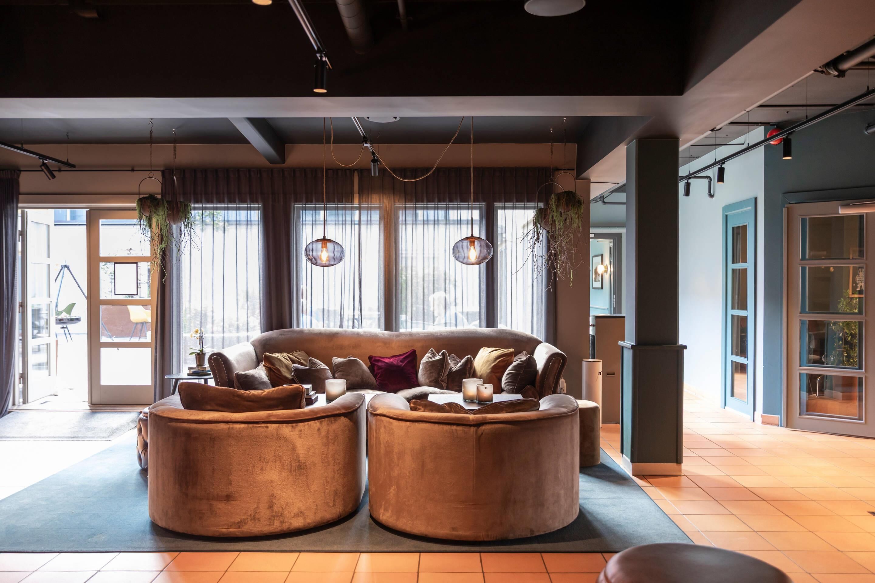 A modern interior with a sofa set, hanging plants, and pendant lighting.