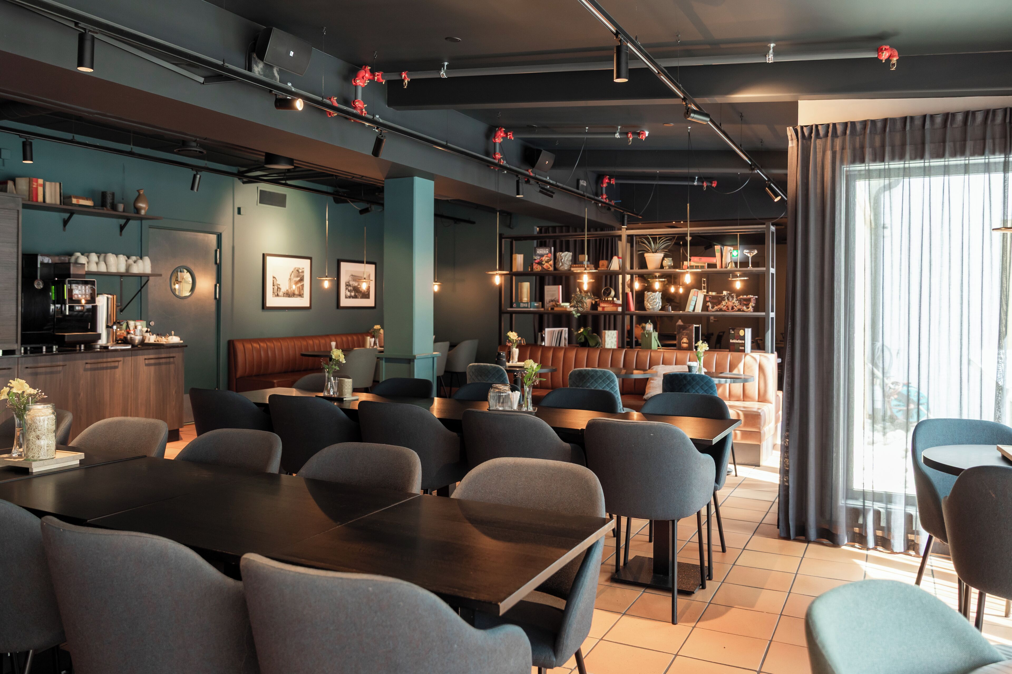 Un restaurante moderno con una mesa común alargada, cabinas y una zona de bar.