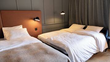Une chambre d’hôtel avec deux lits, une tête de lit, des lampes de chevet et un rideau.