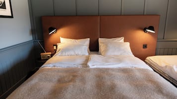 A double bed with a brown headboard, two bedside tables with lamps, and a framed picture on the wall.