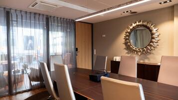 A conference room with a large table, chairs, a projector, and a decorative mirror on the wall.