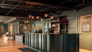 Zona de bar moderna con mostrador, estanterías llenas de botellas y una pizarra de menú.