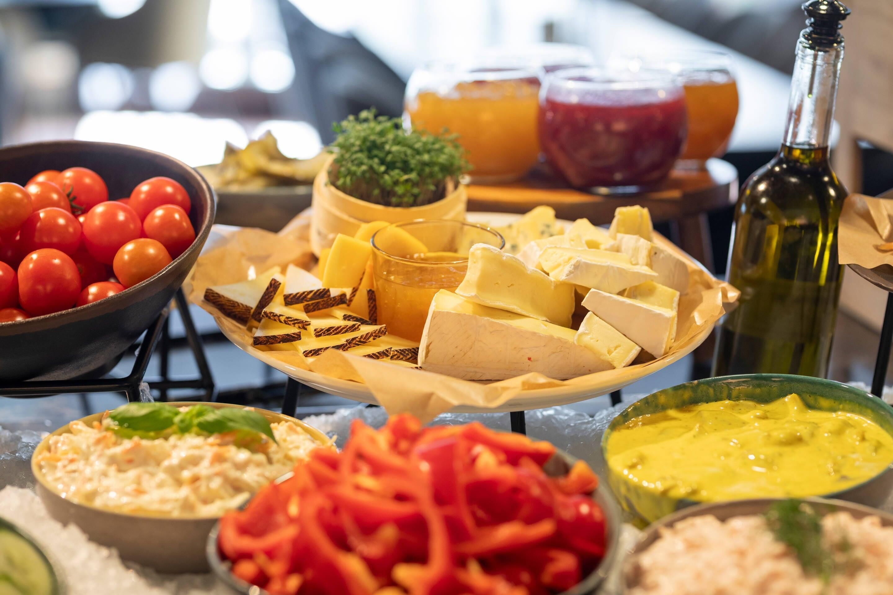 A variety of food items including cheese, tomatoes, and a bottle of wine on a table.