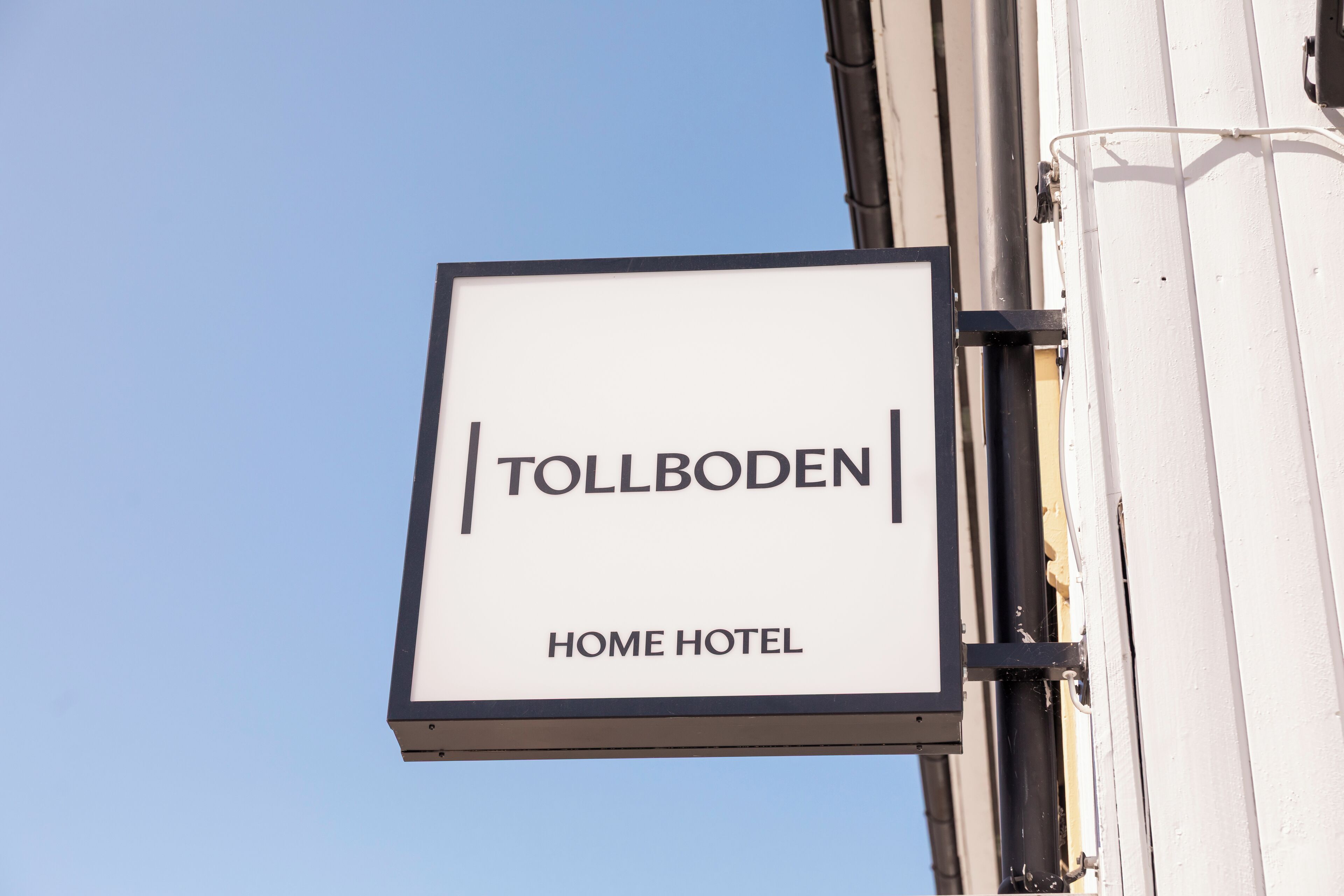 A sign for 'Tollboden Home Hotel' mounted on a building.