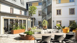 Un patio con mobiliario exterior, plantas en macetas y una escalera que lleva a un piso superior.